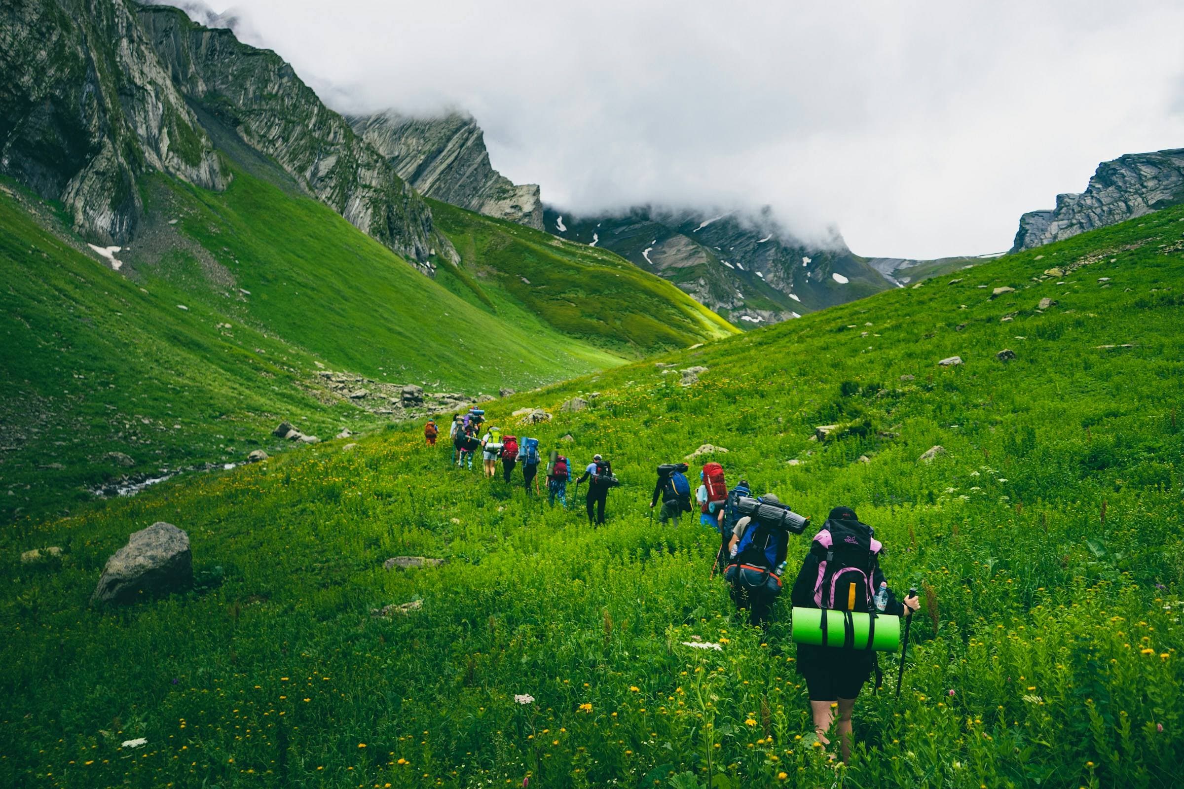 Un groupe de randonneurs en file dans une vallée verte.